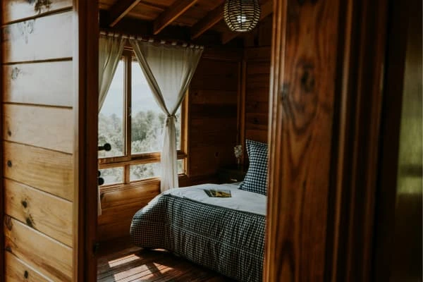Quarto pequeno com paredes e móveis em madeira natural